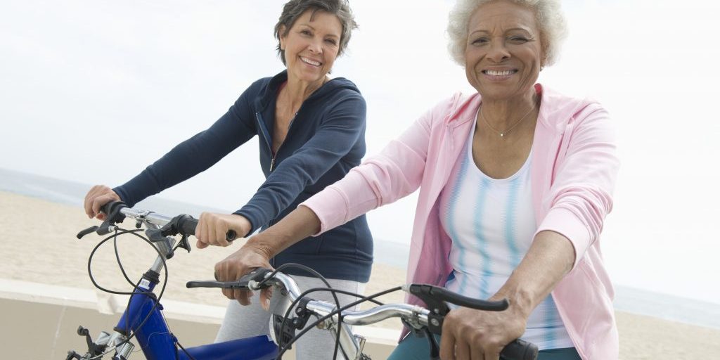 Portrait of happy senior multiethnic female friends riding bicycles together